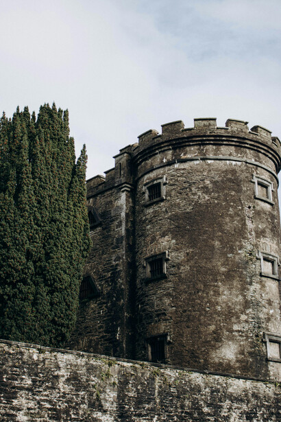 Barred window set into the stone wall of a medieval castle tower in Killarney, Ireland