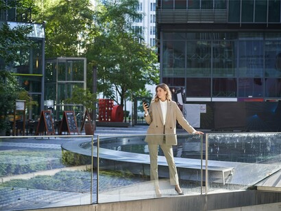 A woman standing in an open urban plaza with clear sightlines and glass buildings, representing the CPTED principle of natural surveillance