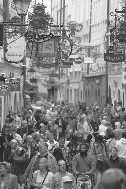 The street was abuzz with a dense crowd, a multitude of people walking, filling the area with the vibrant energy of a lively and bustling cityscape