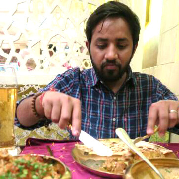 A photo of a Hindu man eating Lucknowi biryani at an Indian restaurant dining table