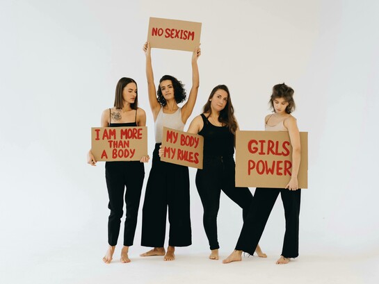 Women in black pants holding placards for women’s rights
