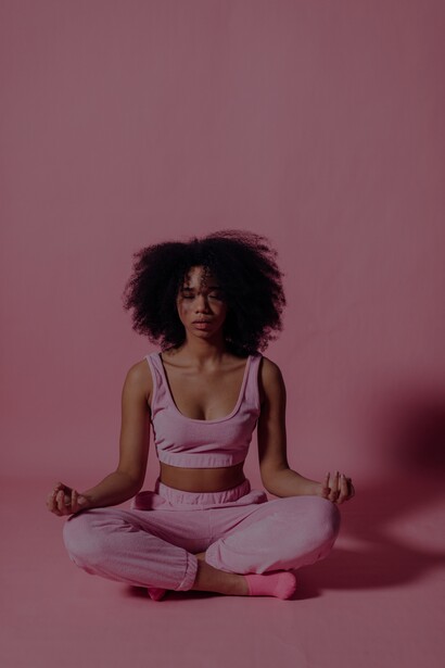 Mulher com top rosa e calças de corrida meditando