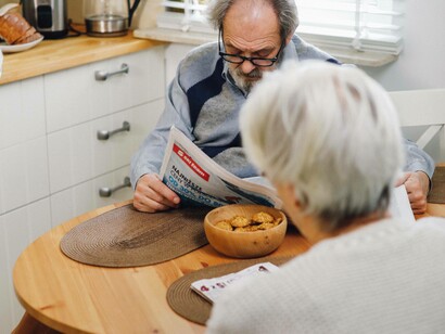 Man reads a newspaper in the presence of his wife