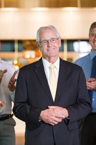 An experienced leader standing confidently before colleagues, proud and smiling