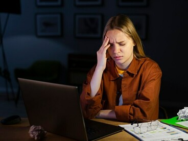 Late at night, a woman sips coffee while working nonstop — a reflection of hustle culture’s toll on wellbeing