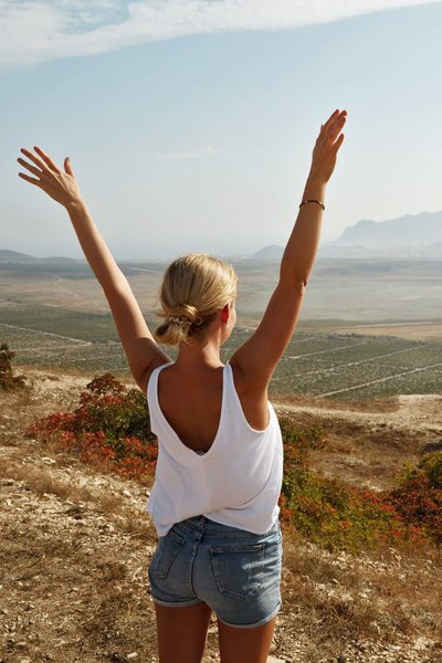 With a gentle smile and wind in her hair, the young blonde woman finds stillness atop a grassy hill, framed by the calm of the natural world