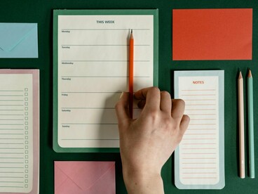 A neatly arranged planning desk with a person holding a pencil, symbolising clarity found through organisation