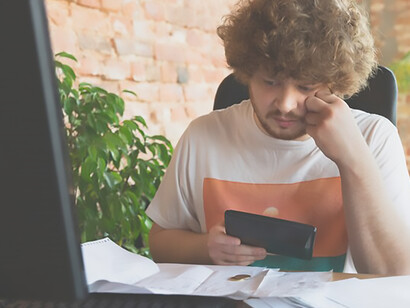 Emotional image capturing a troubled man observing financial and economic graphs in broad daylight, reflecting a sense of despair and hopelessness