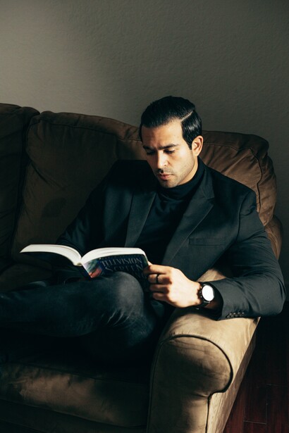 A man reading a book on a sofa, trying to find what path he wants to take