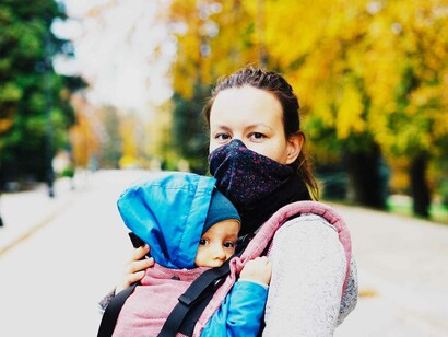 A masked mother holding her child while they take a stroll in the park hoping to make living in the coronavirus world just a little more bearable