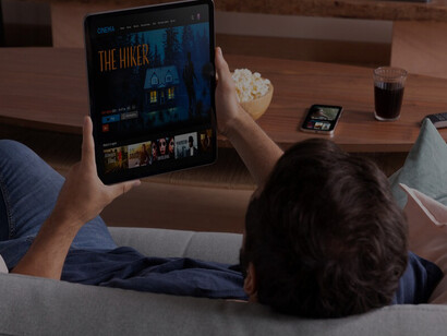 A man browsing movies on his tablet, choosing what to watch on a streaming service