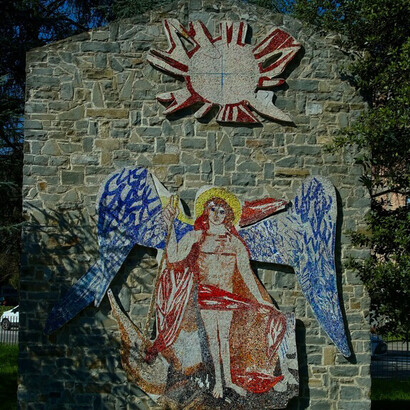 "Saint Michael the Archangel" depicts Saint Michael dominated by the sun, symbol of divine light; at his feet you can see areas of red and black, symbolizing the devil. Saint Michael is the warrior angel who defeats evil. The work was done by Bruno Saetti, born in Bologna in 1902 and passed away in 1984 (the year the work was created)