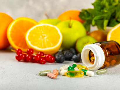 Multivitamins and supplements displayed alongside fresh, healthy fruits on a textured background, showcasing the harmony between diet and nutrition