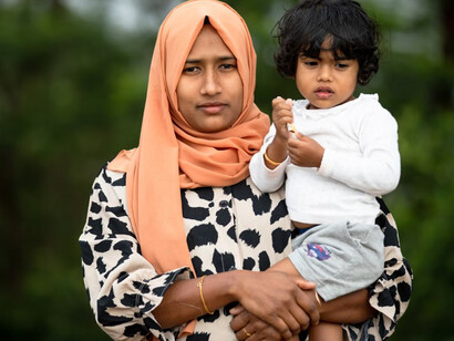 A migrant woman holding a child in her arms