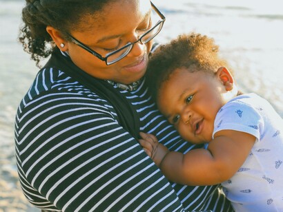 Mother holds baby by beach