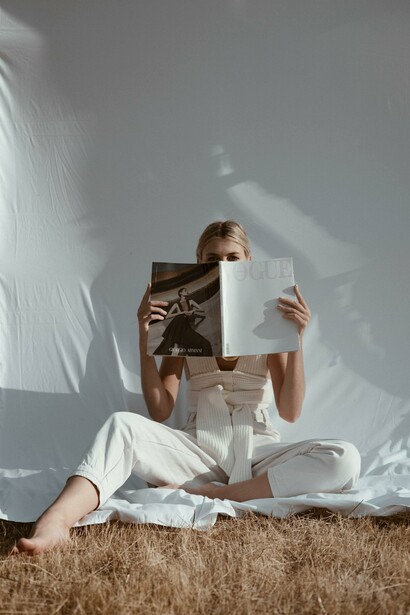 A person in a field with a magazine in front of their face