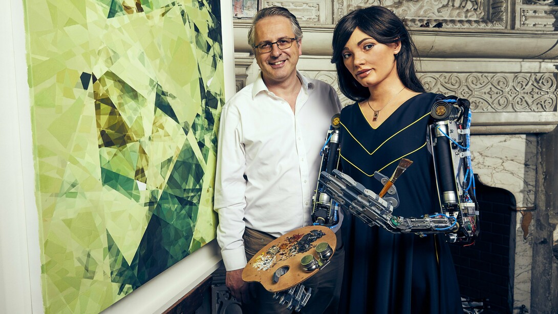 Ai-Da com o galerista Aidan Meller no Reino Unido, 2019. Há décadas, artistas programam algoritmos para criar imagens, sons e textos. Mas então, o que torna a obra de Ai-Da uma novidade?  A novidade não está no seu processo criativo, mas no espetáculo cuidadosamente construído ao seu redor