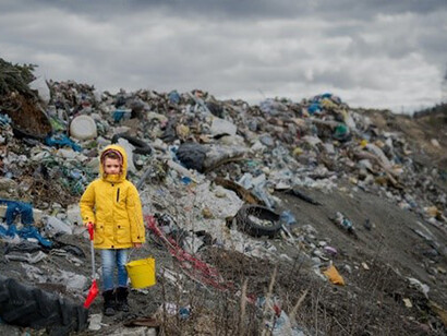Front view of small child standing on landfill, environmental pollution concept