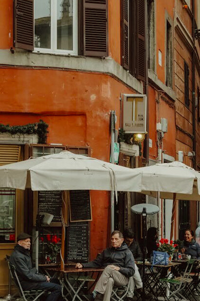 People gathered at a charming street-side restaurant in Rome, Italy, savoring a cozy outdoor dining experience on a pleasant Roman evening