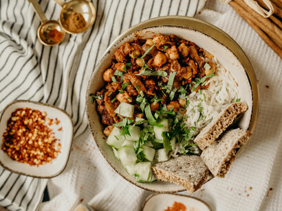 A colorful plant-based meal bowl with chickpeas, cucumbers, chili, and cinnamon, photographed in natural ligh