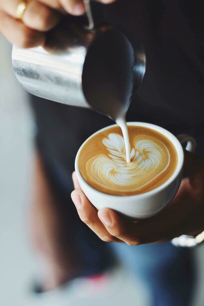 Milk swirls into coffee as it's poured by a barista at a modern coffee startup