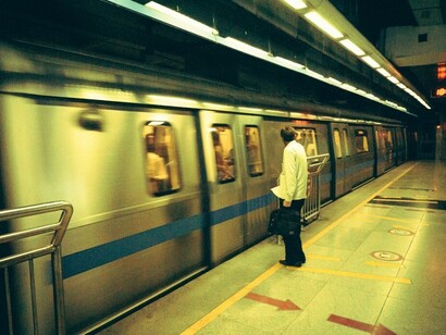A man stands at a crowded subway station in India, watching as a fast-moving train passes by, symbolizing the rapid and often disorienting pace of change in society today