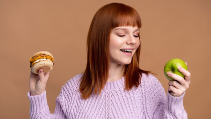 A woman with diabetes carefully deliberating between a hamburger and a donut, making mindful dietary choices to prioritize health