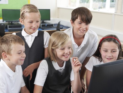 Grupo de niños trabajando de forma colaborativa ante la pantalla de un ordenador