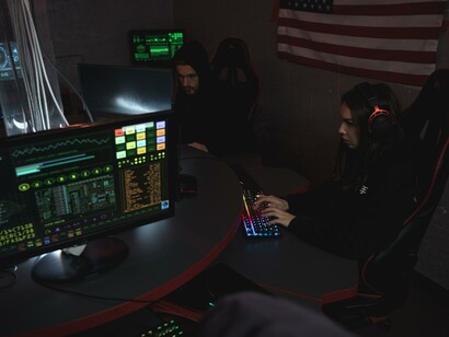 Two people sat in a dark room using computers