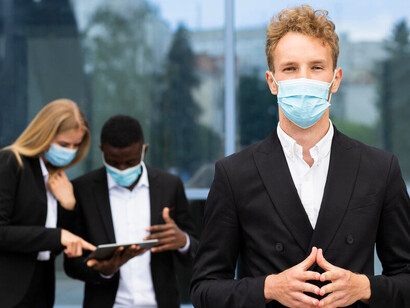 People in masks engaged in work on their laptops, highlighting the blend of productivity and health consciousness during the COVID-19 crisis