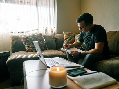 Seated on a couch in the calm of early morning, a man in a black crew-neck t-shirt channels his creativity through sketching