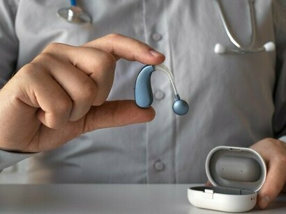 A healthcare professional presenting a compact hearing aid, symbolizing the advancement of wearable technologies