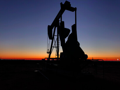 Grúa de construcción y pozo petrolero durante un atardecer