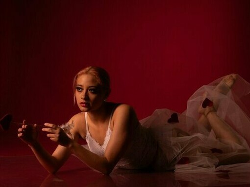 A woman surrounded by shades of red and symbols of affection, representing the fragile nature of emotional attachment