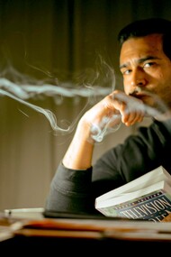 Homem pensativo com livro sentado em quarto esperando a inspiração