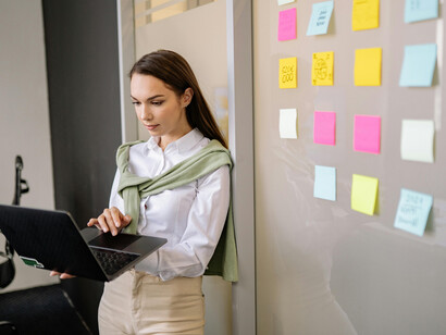 During a business meeting, a confident woman with a laptop mentors a colleague and presents her ideas to the team