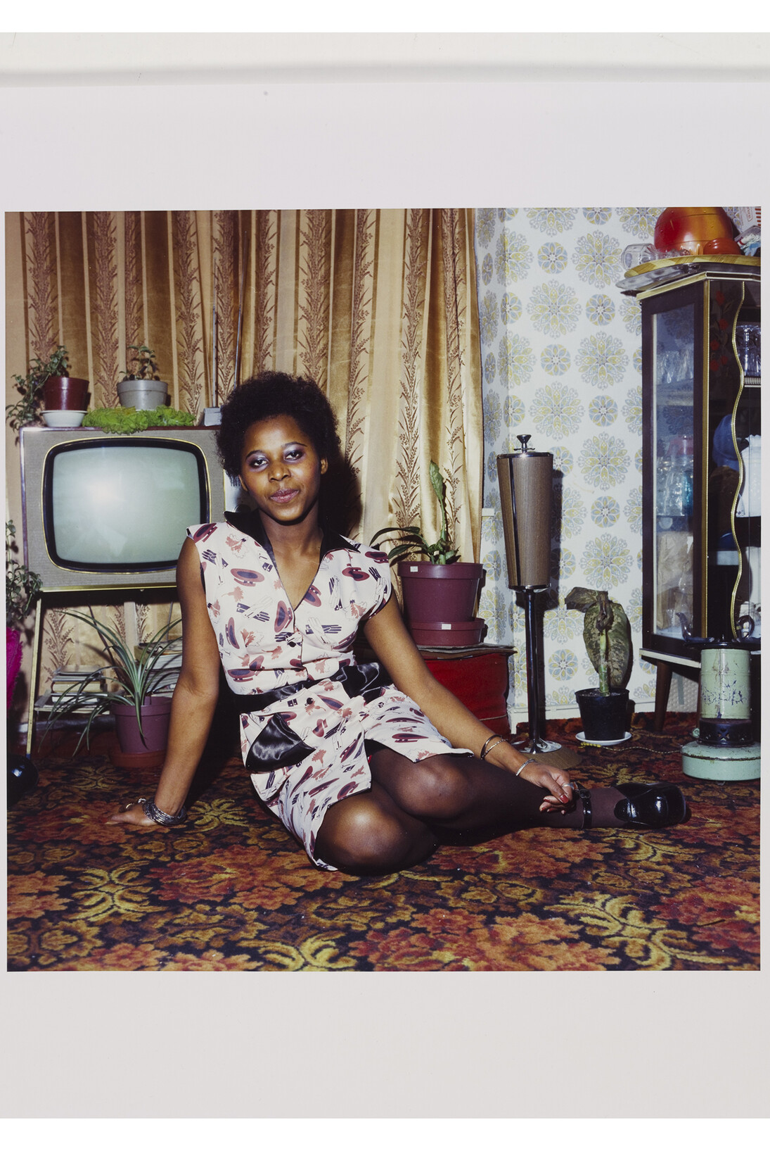 Neil Kenlock, ‘Untitled [Young woman seated on the floor at home in front of her television set]', C- type print, London, 1972 © Neil Kenlock / Victoria and Albert, London