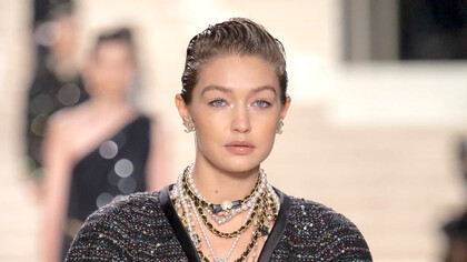 Modelo usa brincos Chanel, colares de pérolas e com detalhes pretos e dourados