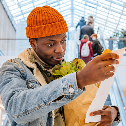 An African American shopper examines a receipt with concern in a mall, highlighting financial pressures and economic uncertainty