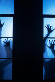 Spooky zombie hands pressing against a windowpane in the dead of night