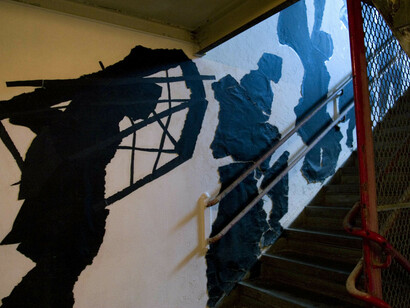 William Kentridge: Stair Procession
This site-specific installation was curated by Carolyn Christov-Bakargiev as part of P.S.1’s Vertical Painting series initiated by Alanna Heiss in 1997. Created for P.S.1’s northwest stairwell, Stair Procession is a white-on-black drawing similar to white chalk graffiti. The constricted nature of the staircase played a role in the artist’s decision to use anamorphic distortions. Kentridge evokes the building’s original function as a public school in establishing both the subject matter and method.

William Kentridge. Stair Procession. 2000. © 2017 William Kentridge. Photo: John Berens