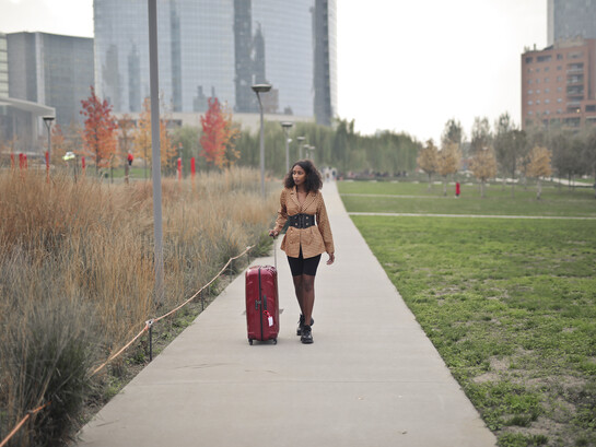 Young woman walking down a city street with a suitcase