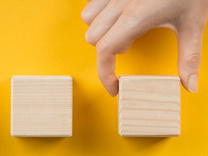 A hand carefully arranges wooden blocks, illustrating the importance of breaking down a complex problem into manageable parts