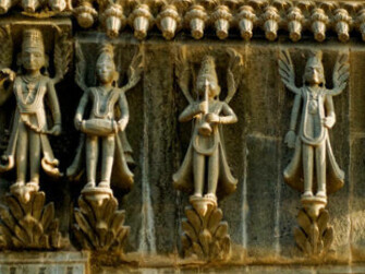 The stone carvings of Gandharvas, divine celestial singers playing music, adorn the gate of Maheshwar Temple in Madhya Pradesh, India