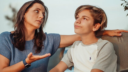 A mother earnestly engages in conversation with her teenage son, seeking to connect and communicate with understanding