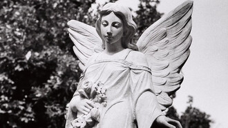 A black and white photograph of an angel statue in a cemetery