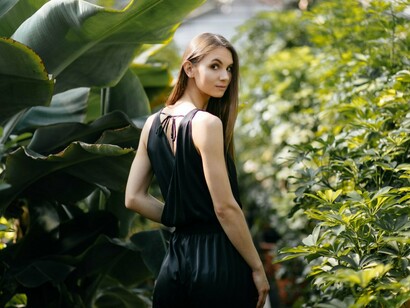 A woman standing in a lush greenhouse aisle, representing the fine line between who she was and who she is becoming