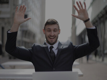A man in a sharp black suit raises both his hands gracefully