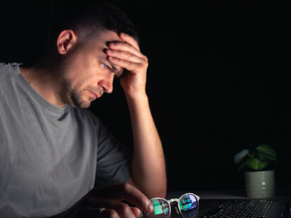 A young man working at his computer late at night, upset