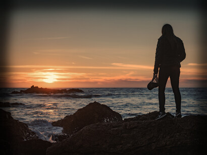 A woman watches the sun set on the ocean